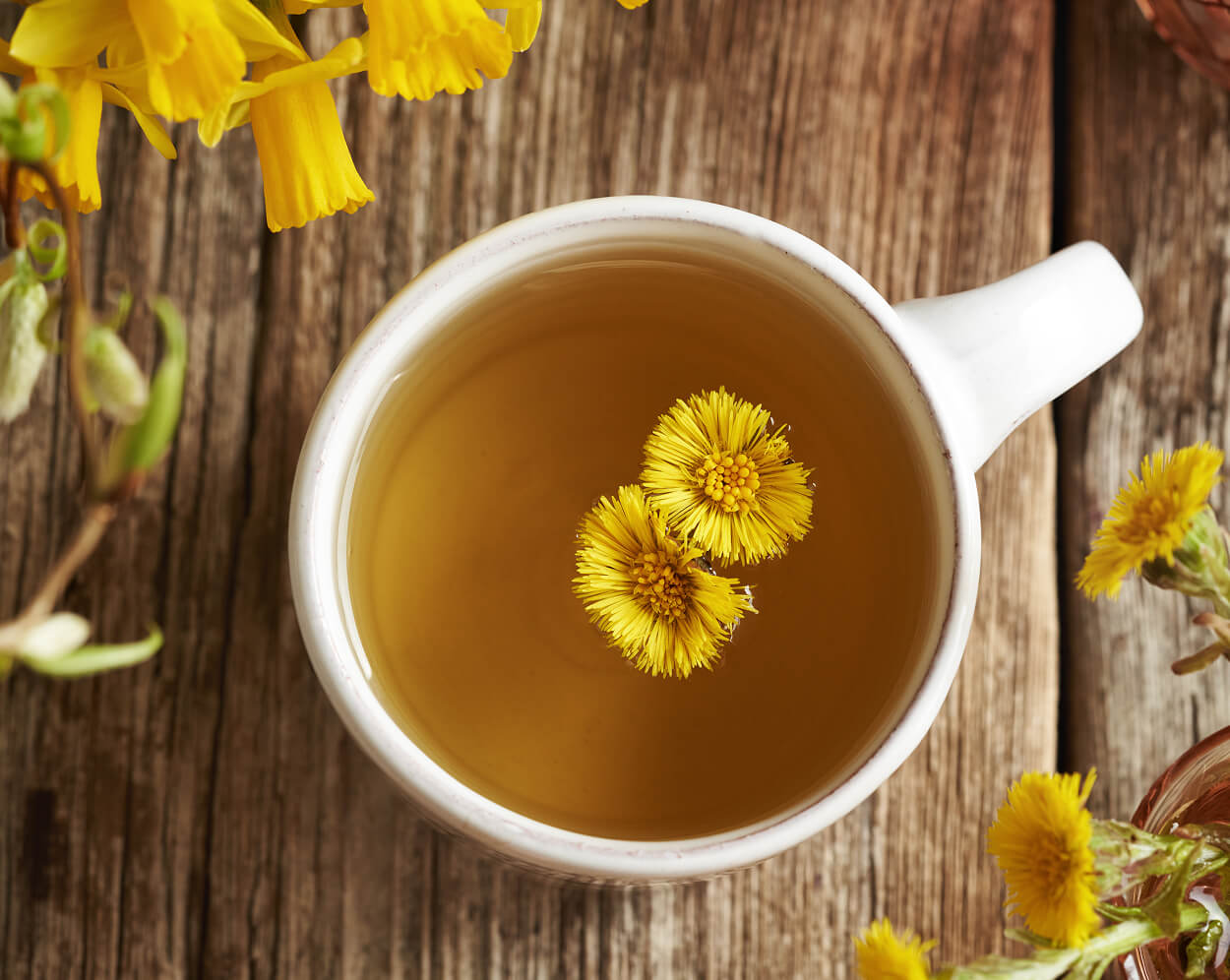 Dandelion root tea with two flowers floating on top.