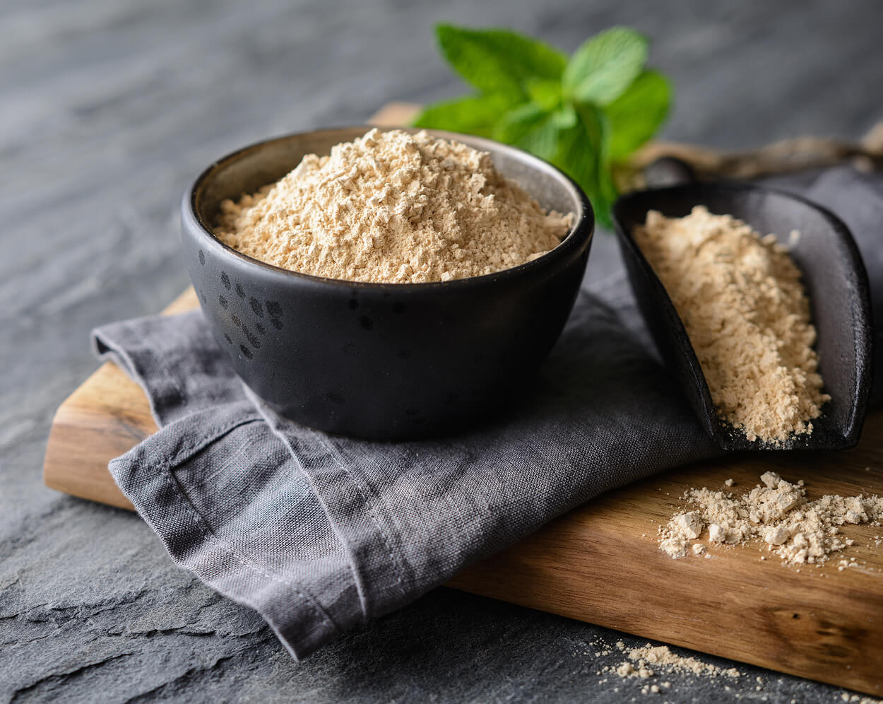 Macca root powder in a black bowl with a scoop.