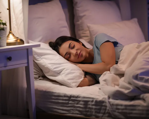 Peaceful woman sleeping comfortably in bed with soft lighting, representing restful sleep and relaxation