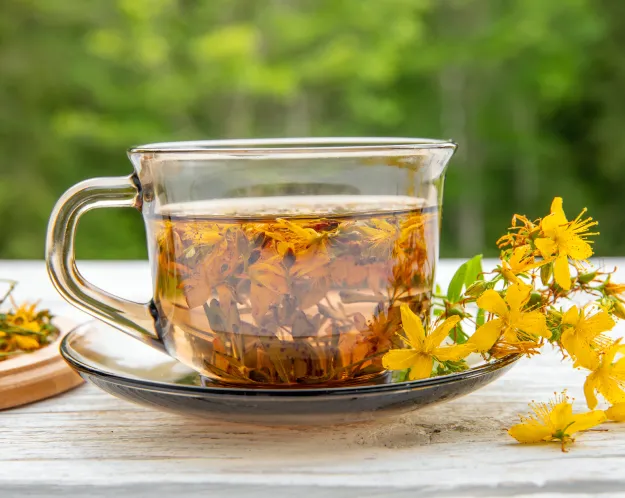 A glass cup of herbal tea with St. John's Wort flowers, symbolizing natural remedies for stress and anxiety.