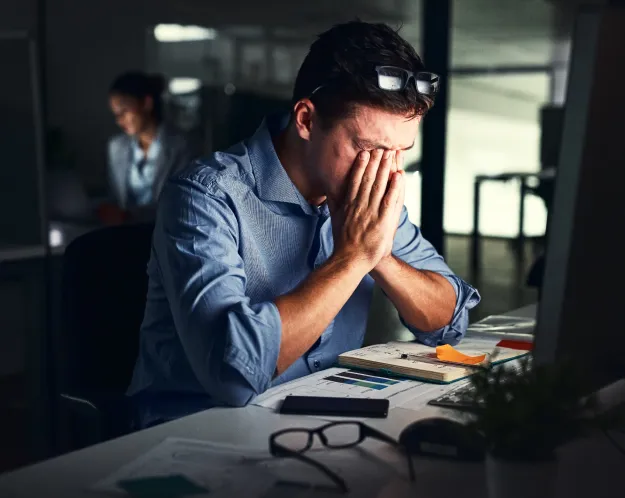 Stressed man at his desk with hands on his face